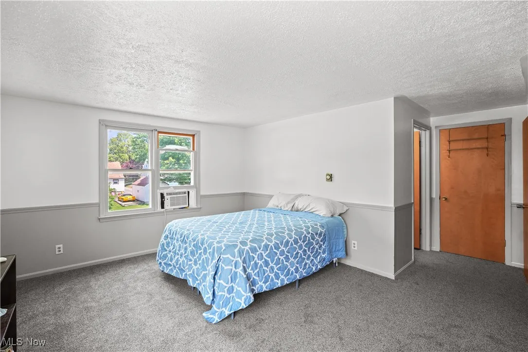 Carpeted bedroom featuring a textured ceiling and baseboards
