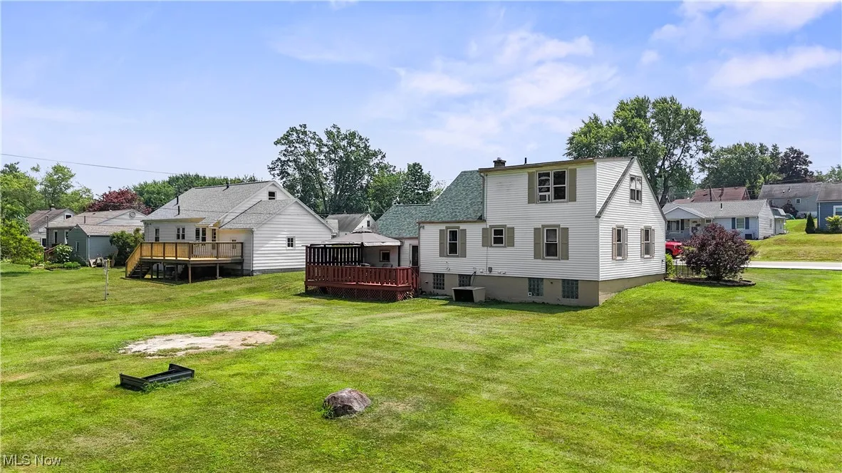 Rear view of house with a wooden deck and a lawn