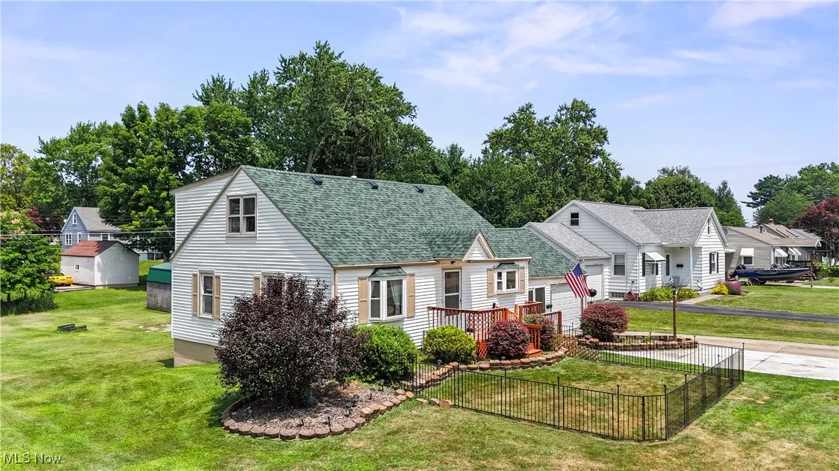 Bungalow-style home featuring roof with shingles and view of wooded area
