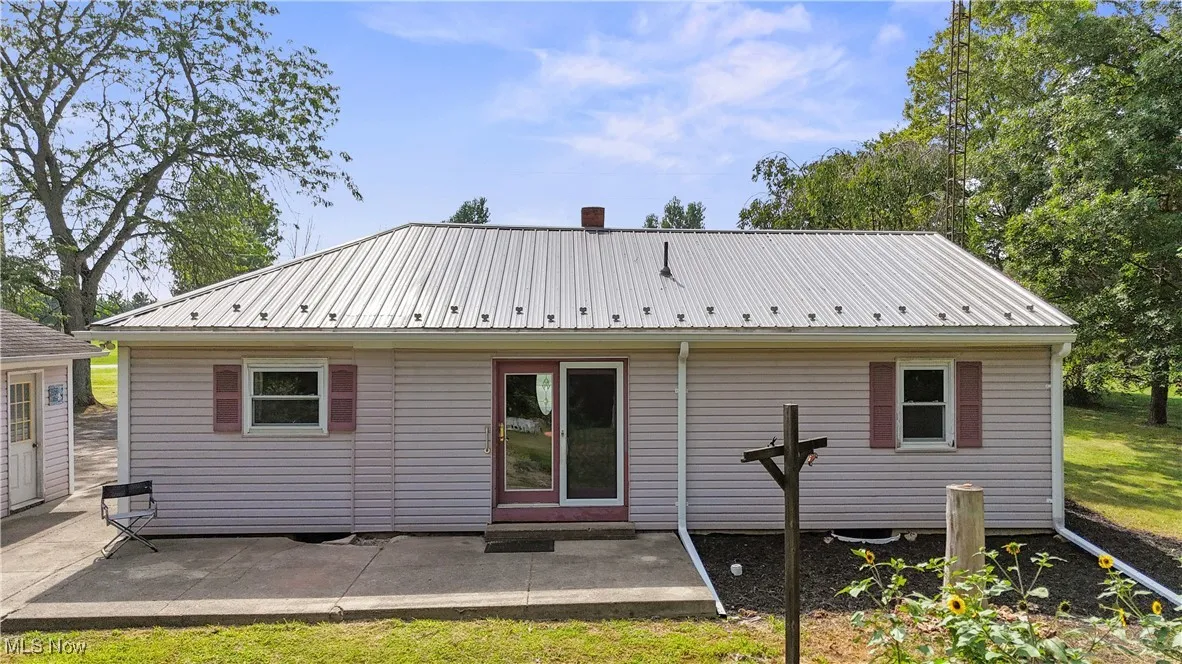 Rear view of property featuring a metal roof and a patio area