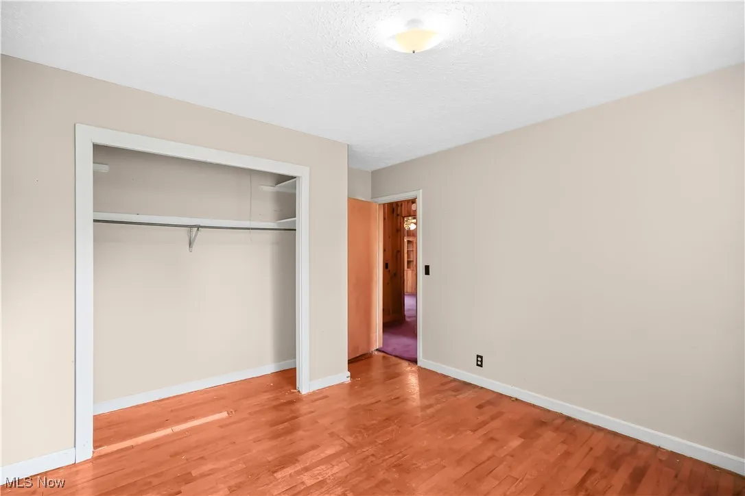 Unfurnished bedroom featuring light wood-style floors, a closet, and a textured ceiling