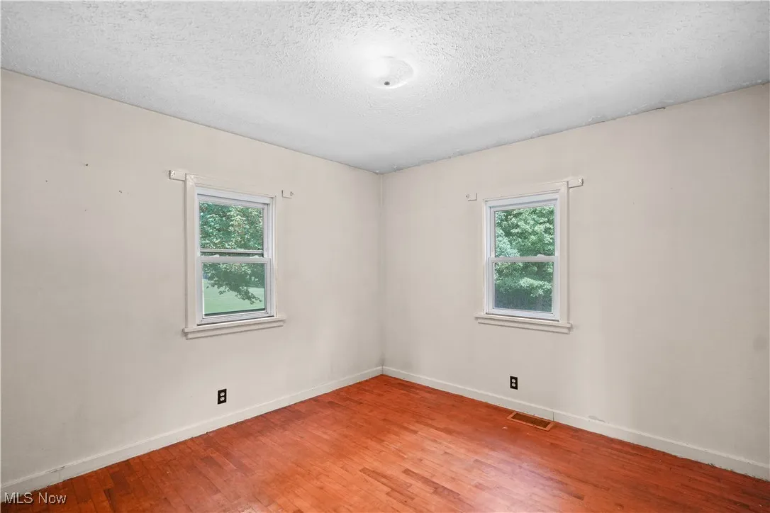 Empty room with healthy amount of natural light, light wood finished floors, and a textured ceiling