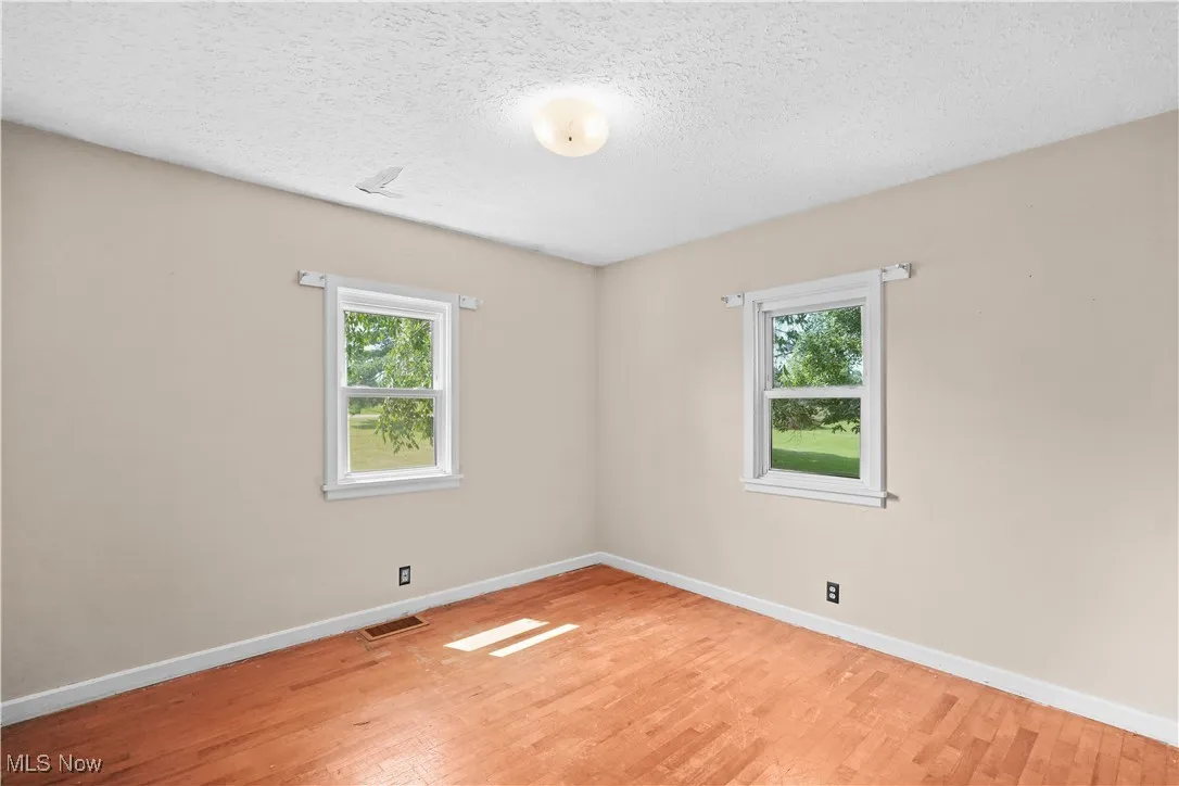 Unfurnished room featuring light wood-style flooring, healthy amount of natural light, and a textured ceiling