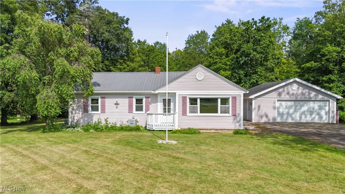 Ranch-style house featuring an outbuilding, a metal roof, a detached garage, and a front lawn