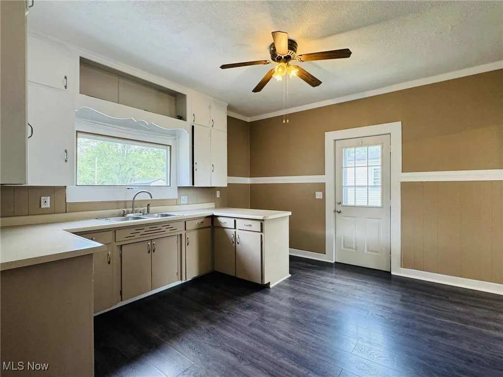 Kitchen featuring dark wood-style floors, a ceiling fan, healthy amount of natural light, light countertops, and a textured ceiling