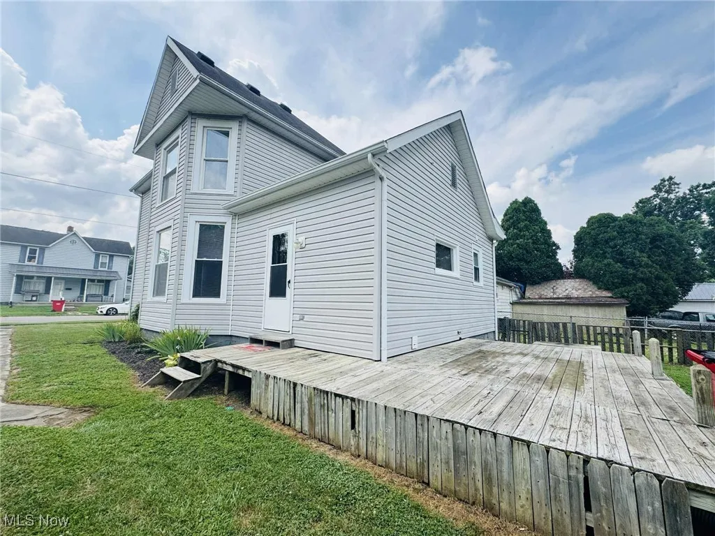 Back of house with a deck and a yard