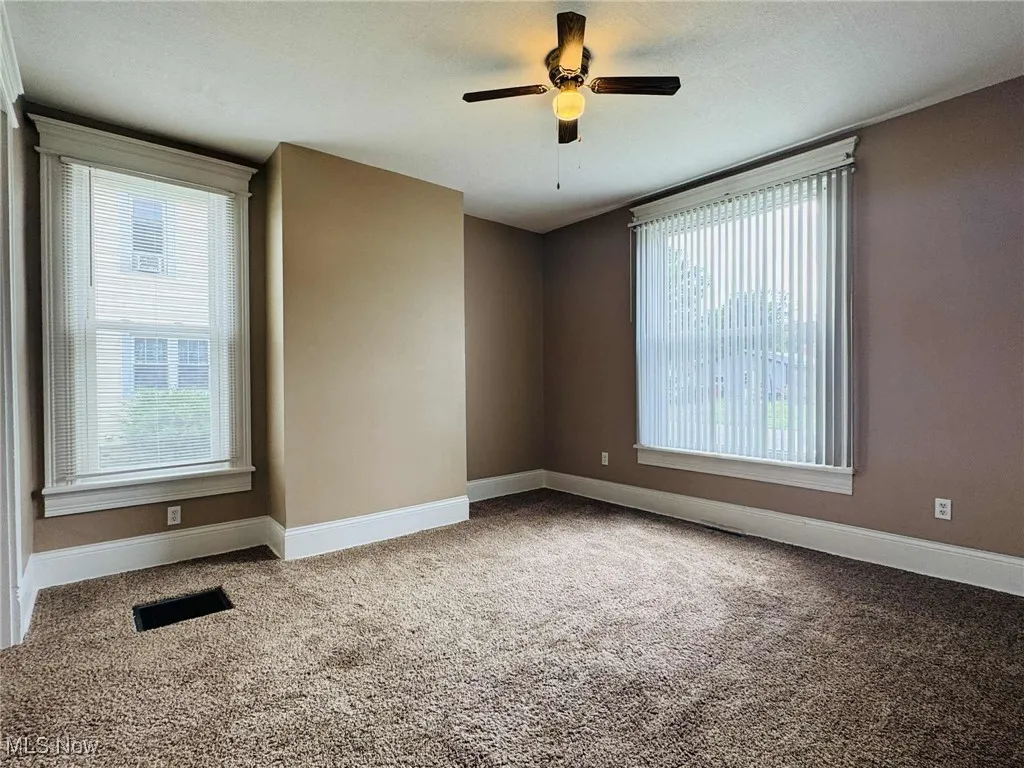 Empty room featuring carpet flooring, healthy amount of natural light, and ceiling fan