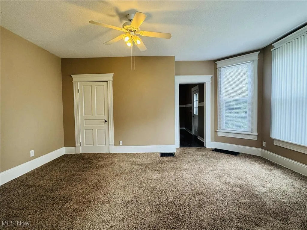 Spare room featuring carpet flooring, a ceiling fan, and a textured ceiling