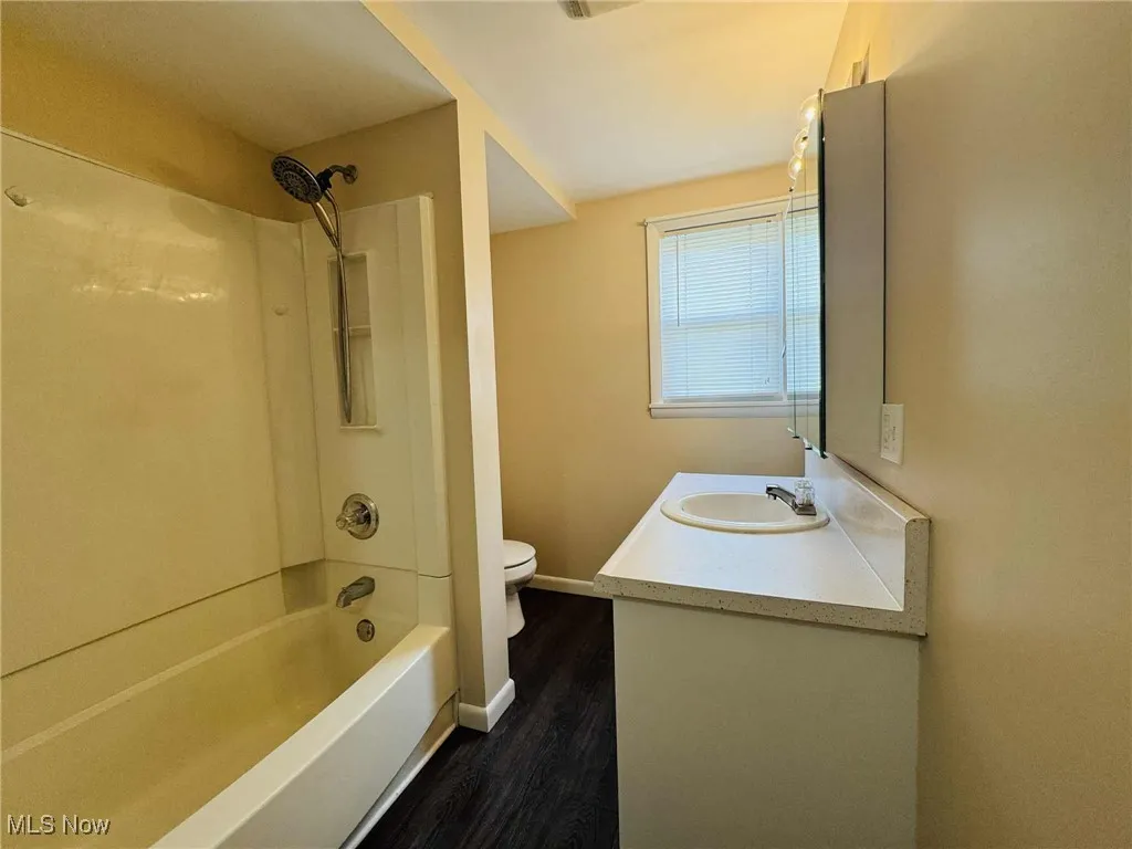 Bathroom with vanity, wood finished floors, and shower / washtub combination