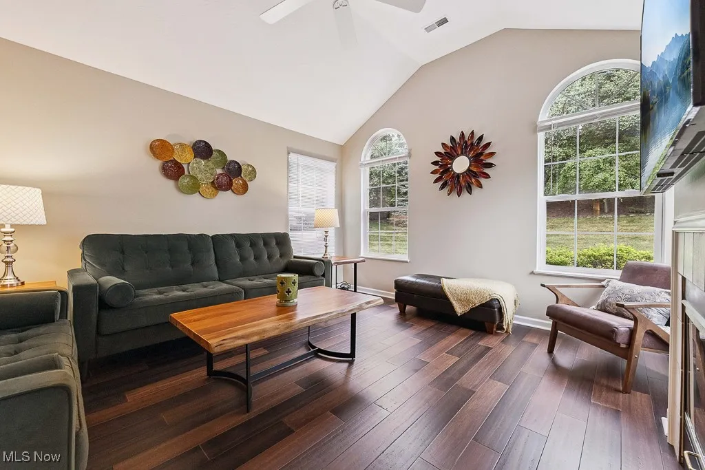 Living area featuring dark wood finished floors, lofted ceiling, plenty of natural light, and ceiling fan