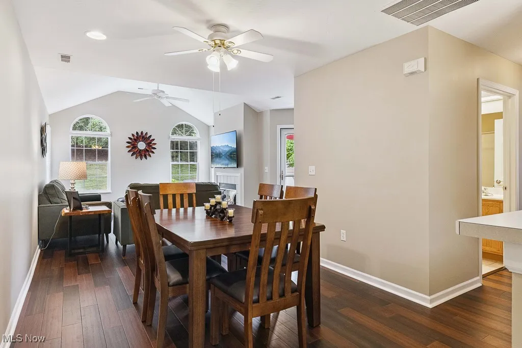 Dining room with dark wood-style floors, ceiling fan, and vaulted ceiling