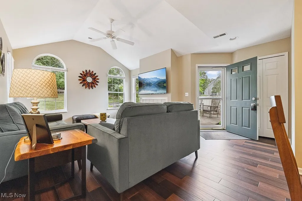 Living room with healthy amount of natural light, ceiling fan, hardwood / wood-style floors, and vaulted ceiling