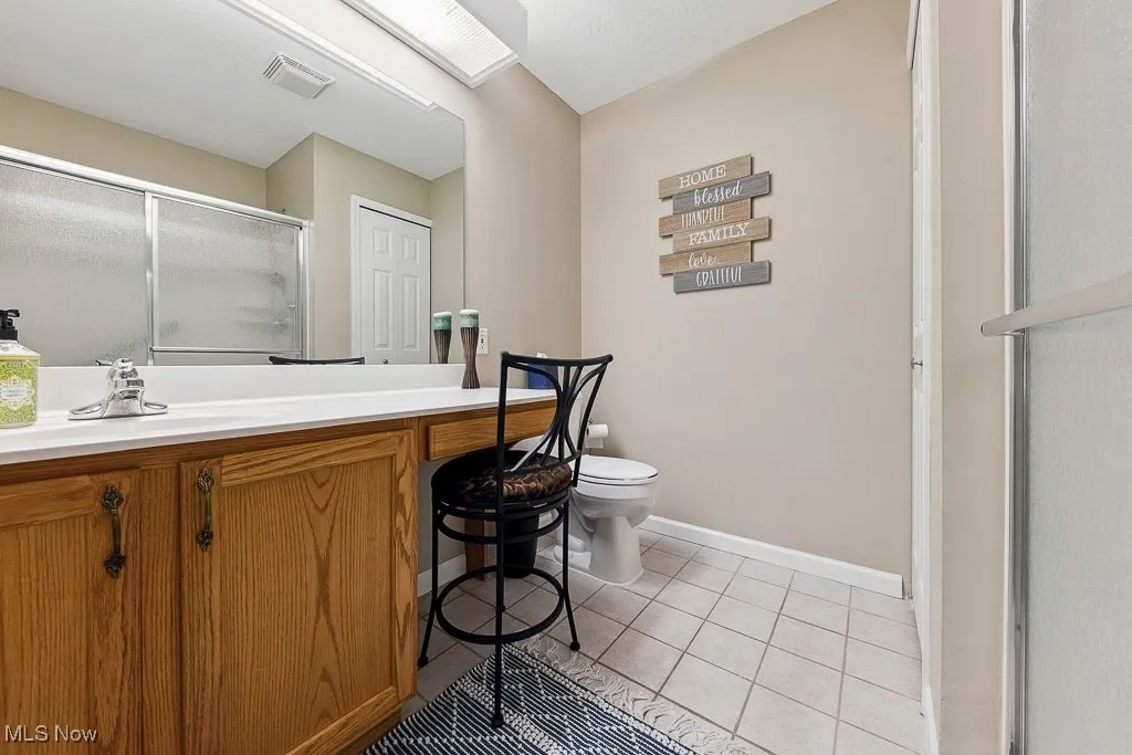 Full bathroom with a shower with shower door, vanity, and tile patterned floors