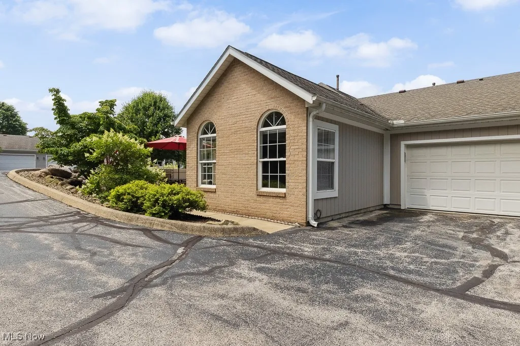 View of home's exterior with brick siding, roof with shingles, asphalt driveway, and an attached garage