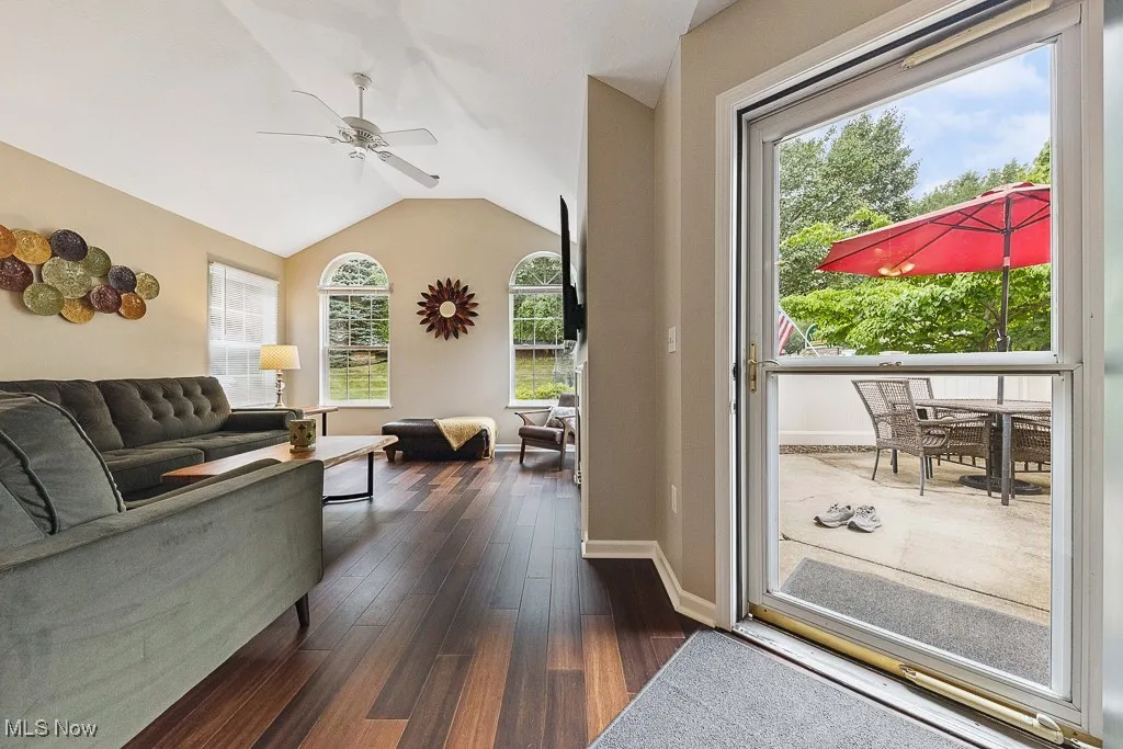 Living room with dark wood finished floors, ceiling fan, and vaulted ceiling