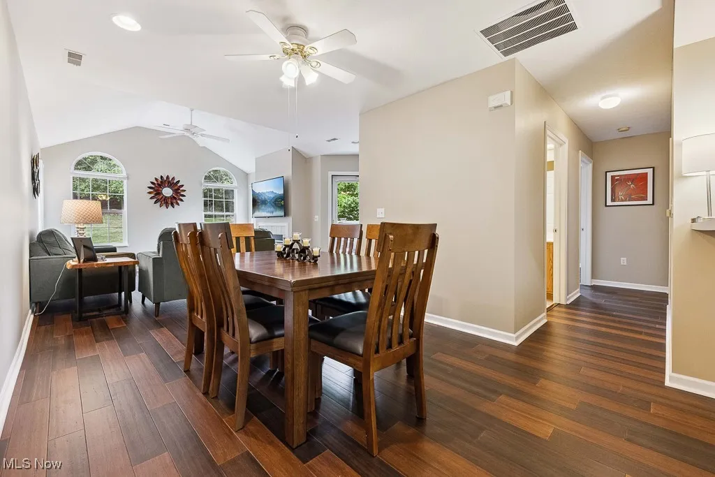Dining area with a ceiling fan, wood finished floors, and vaulted ceiling