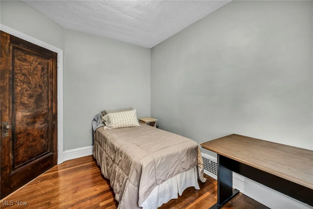 Bedroom featuring wood finished floors, a textured ceiling, and a desk