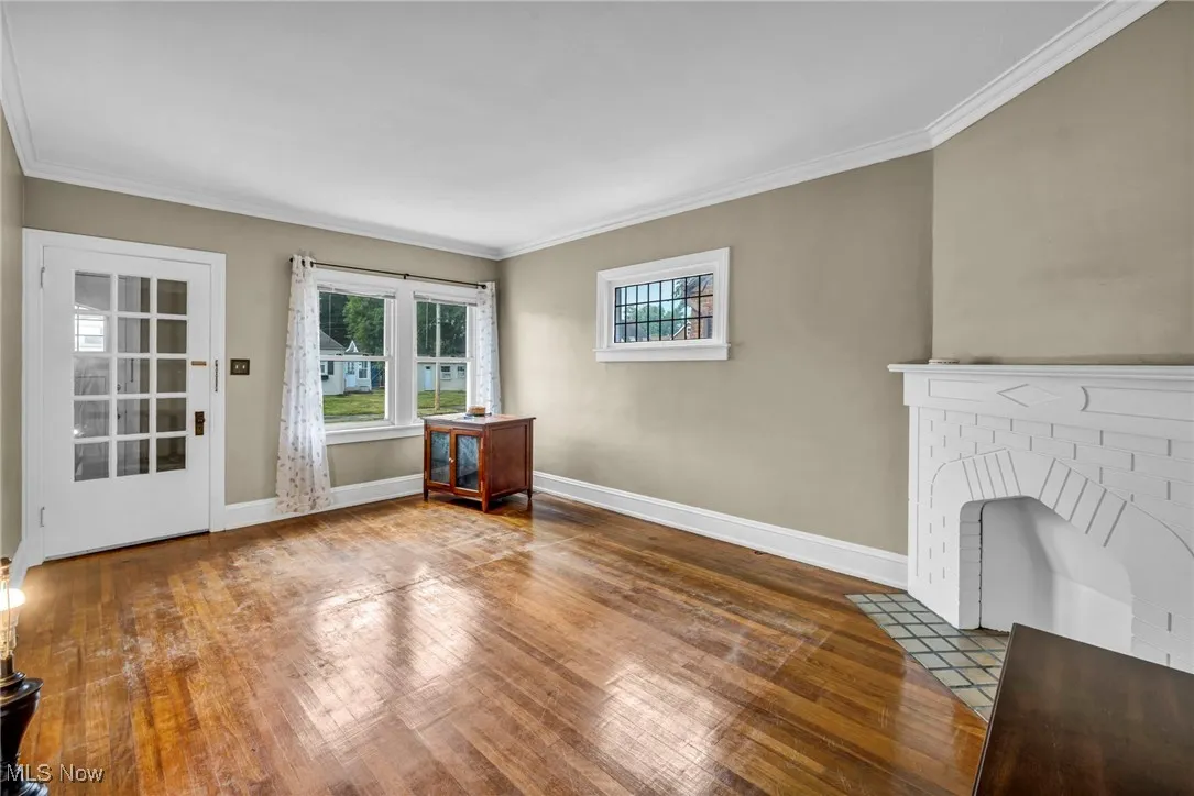 Unfurnished living room with hardwood / wood-style flooring and crown molding