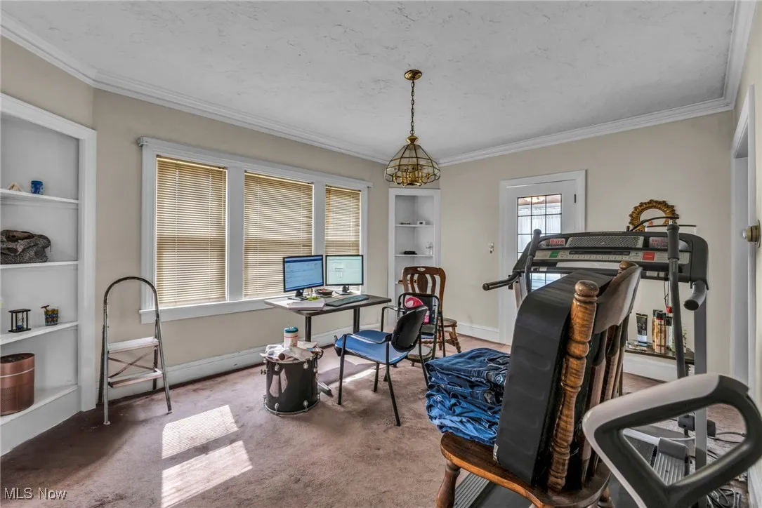 Exercise area with carpet floors, ornamental molding, built in shelves, a chandelier, and a textured ceiling