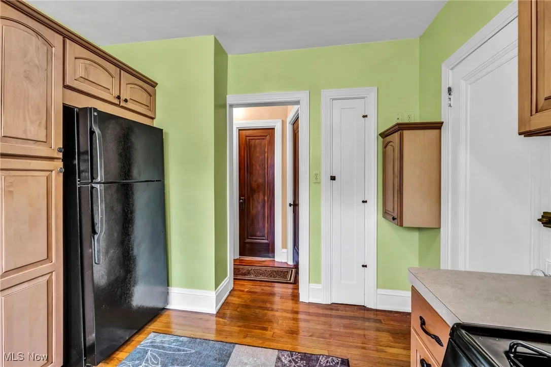 Kitchen with black appliances, wood finished floors, and light countertops