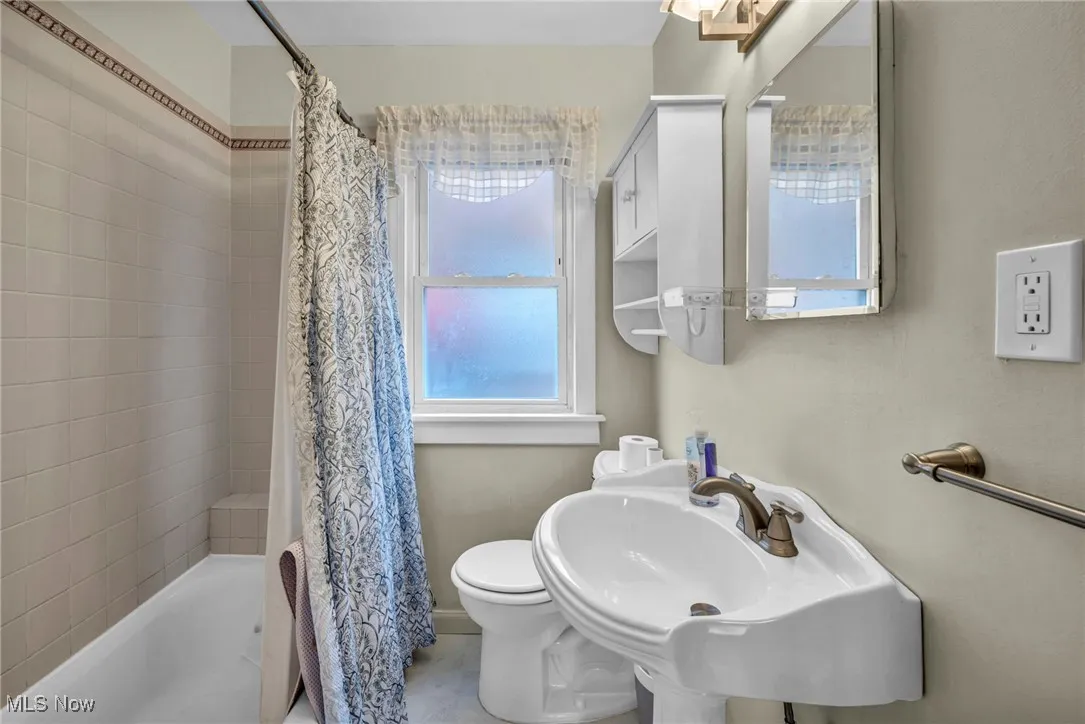 Full bathroom featuring healthy amount of natural light and shower / tub combo with curtain