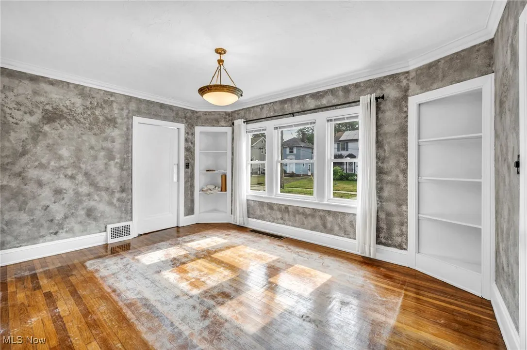 Unfurnished dining area with hardwood / wood-style flooring, built in features, and ornamental molding