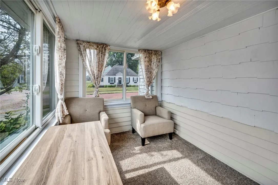 Sunroom featuring carpet and wooden walls