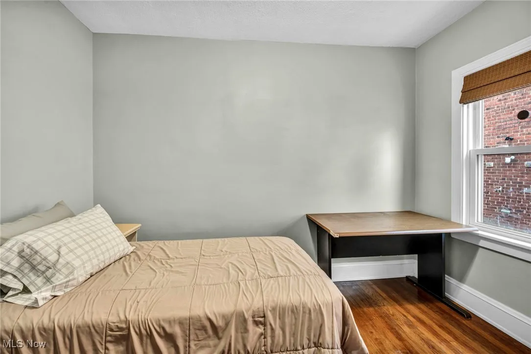 Bedroom with dark wood-type flooring and baseboards