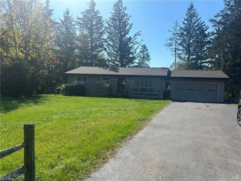Single story home featuring an attached garage, asphalt driveway, and a front yard