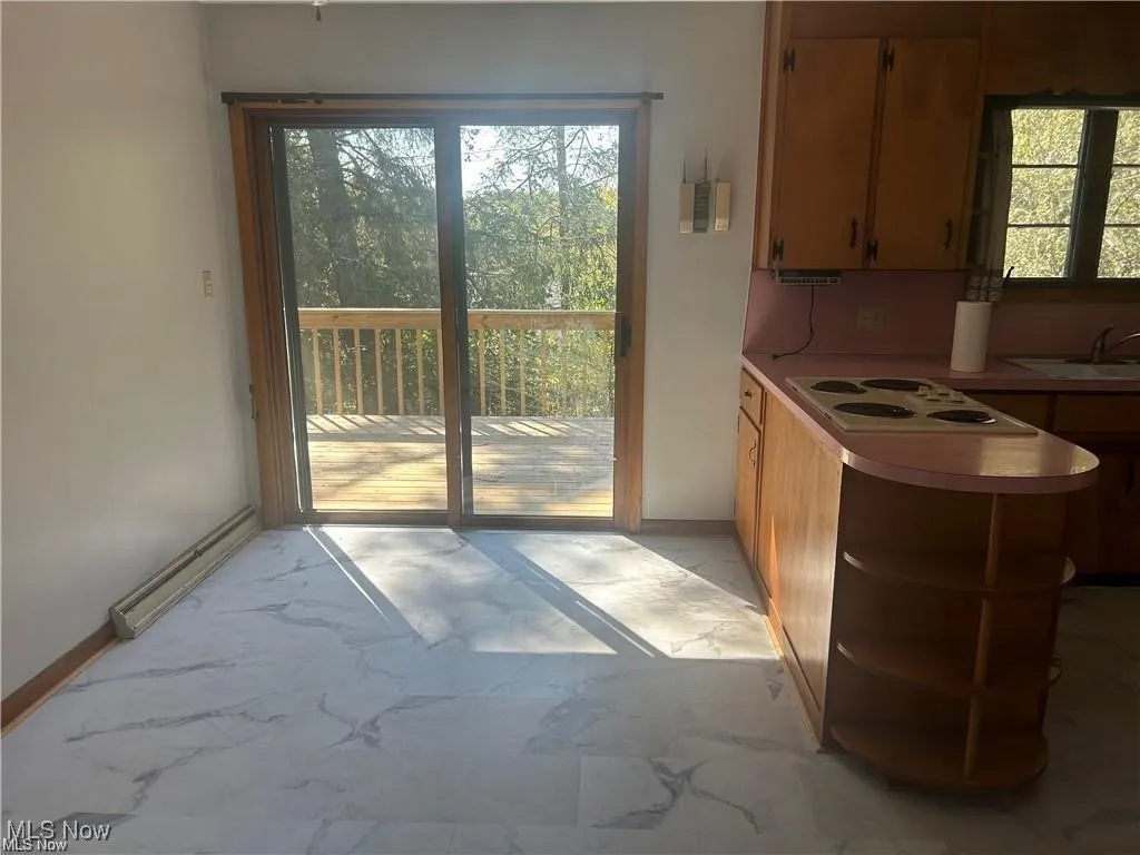 Kitchen featuring plenty of natural light, light countertops, light marble finish floors, and white electric cooktop