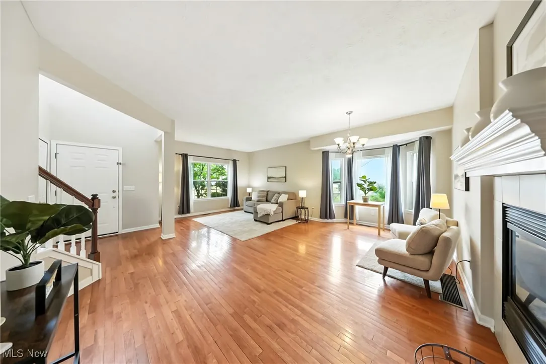 Living area with stairs, a chandelier, light wood-style flooring, and a tile fireplace