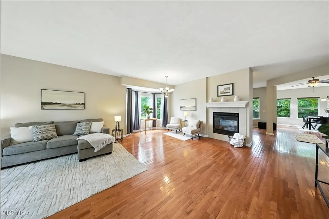 Living area featuring a chandelier, light wood-style floors, a tiled fireplace, and a ceiling fan