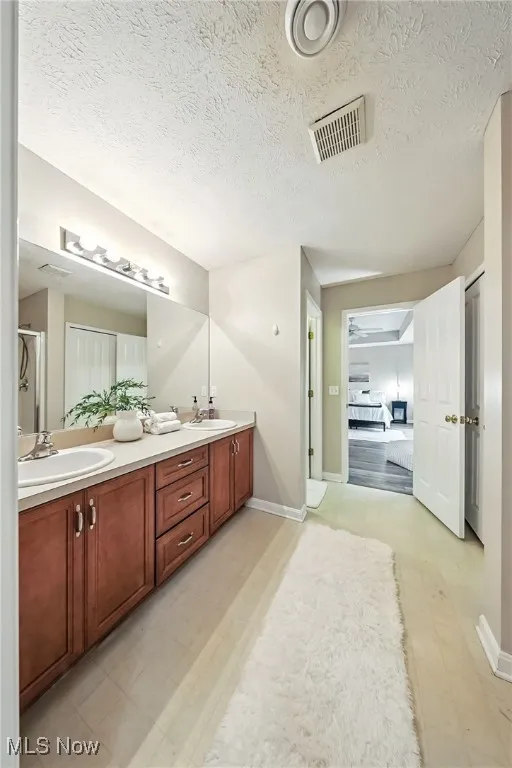 Bathroom with double vanity, a textured ceiling, and tile patterned floors