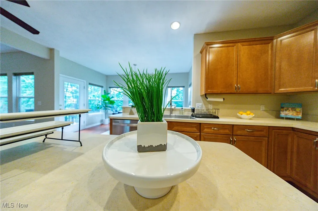 Kitchen with brown cabinetry, light countertops, recessed lighting, dishwasher, and ceiling fan