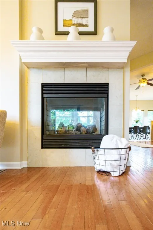 Detailed view of wood finished floors, a fireplace, and a ceiling fan