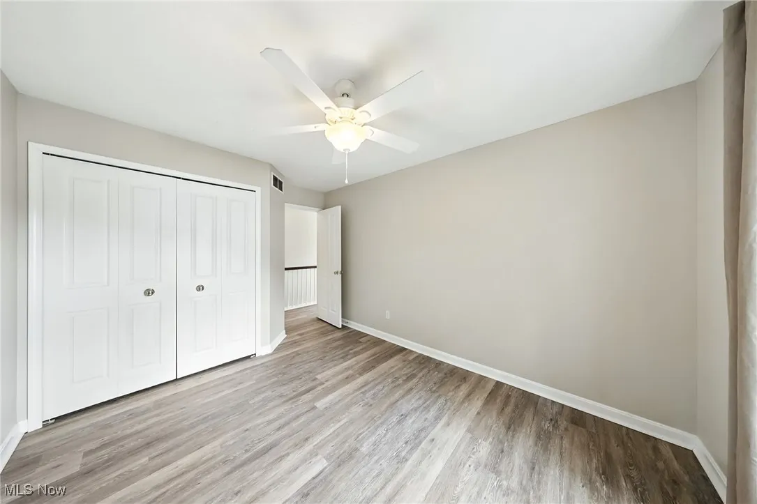 Unfurnished bedroom featuring wood finished floors, a closet, and a ceiling fan