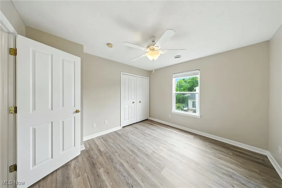 Unfurnished bedroom with wood finished floors, a closet, and a ceiling fan