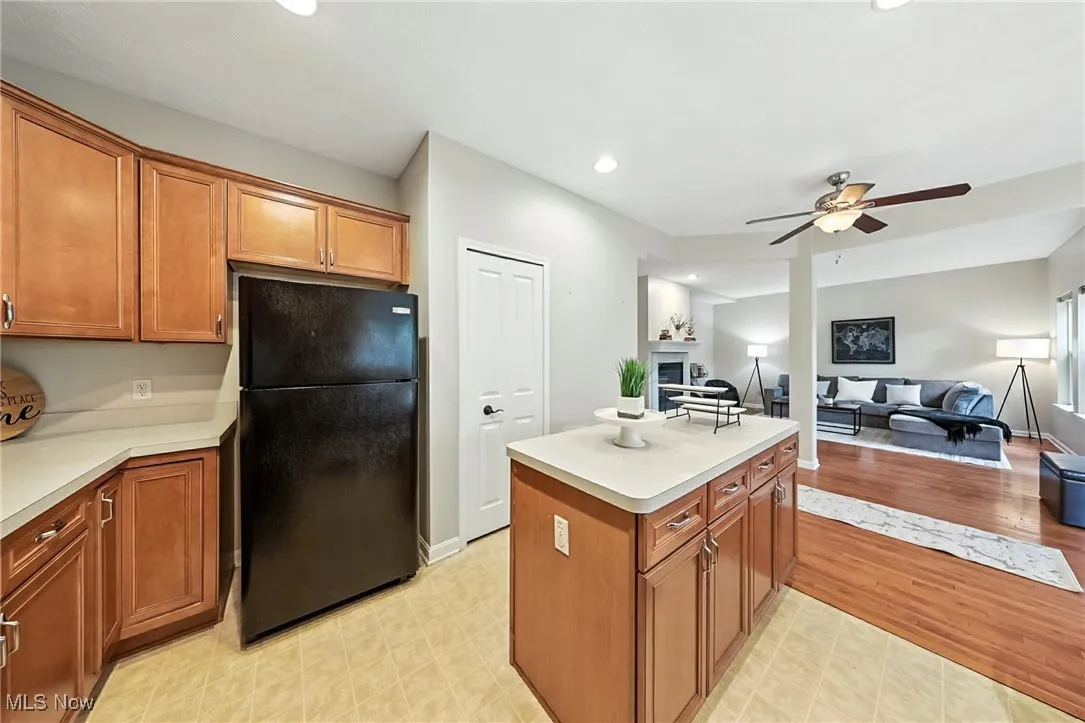 Kitchen with freestanding refrigerator, a ceiling fan, light countertops, brown cabinetry, and recessed lighting