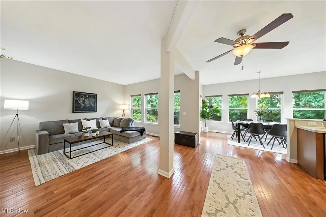 Living room with a ceiling fan, light wood finished floors, and vaulted ceiling