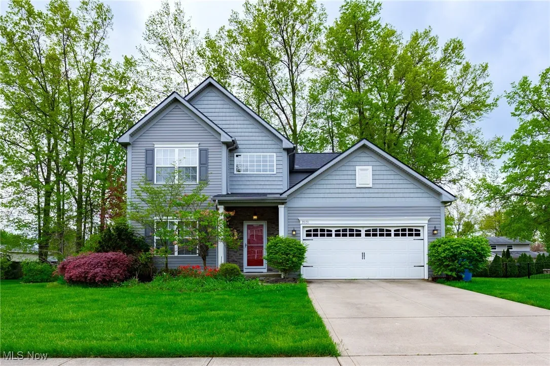 Traditional-style home with an attached garage, a front yard, and driveway