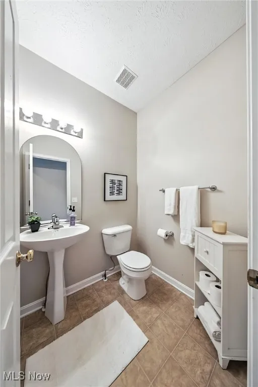 Half bathroom featuring tile patterned floors and a textured ceiling