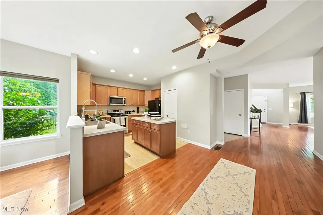 Kitchen featuring stainless steel appliances, light countertops, light wood-style flooring, ceiling fan, and recessed lighting