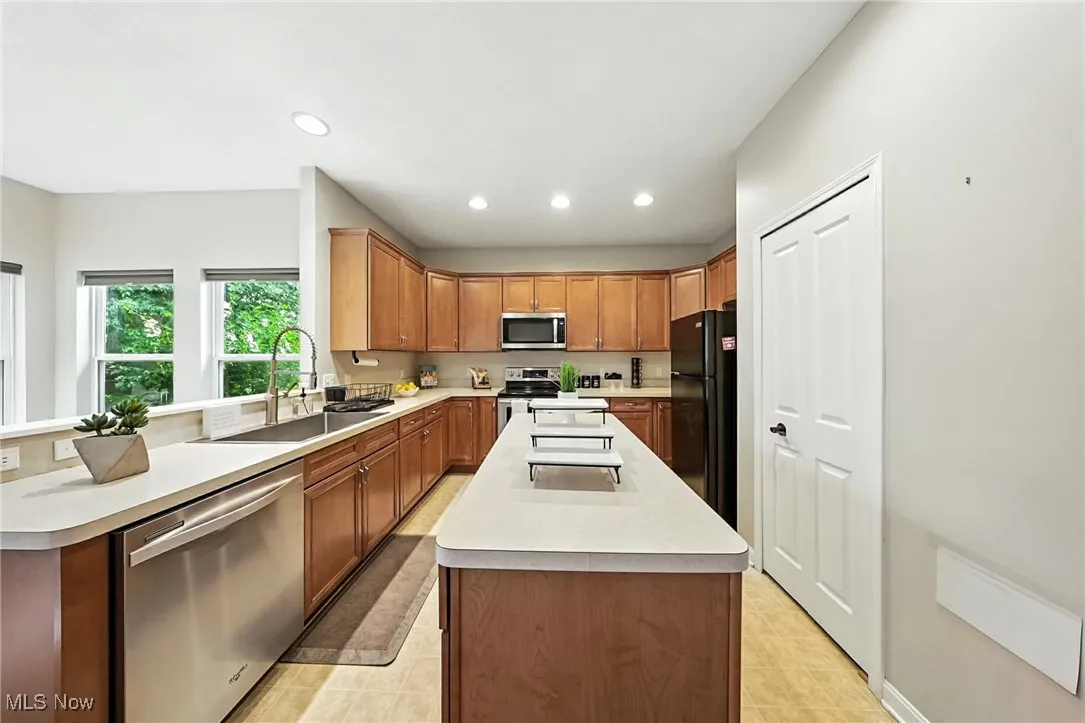 Kitchen featuring stainless steel appliances, light countertops, a center island, recessed lighting, and a peninsula