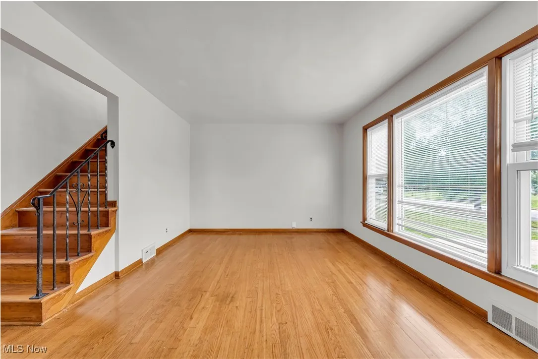 Unfurnished living room featuring light wood-style flooring and stairs