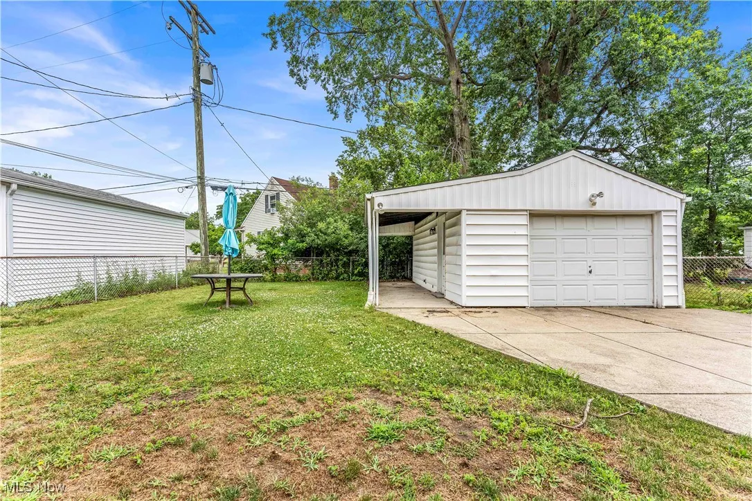 View of yard with a garage, an outbuilding, and driveway