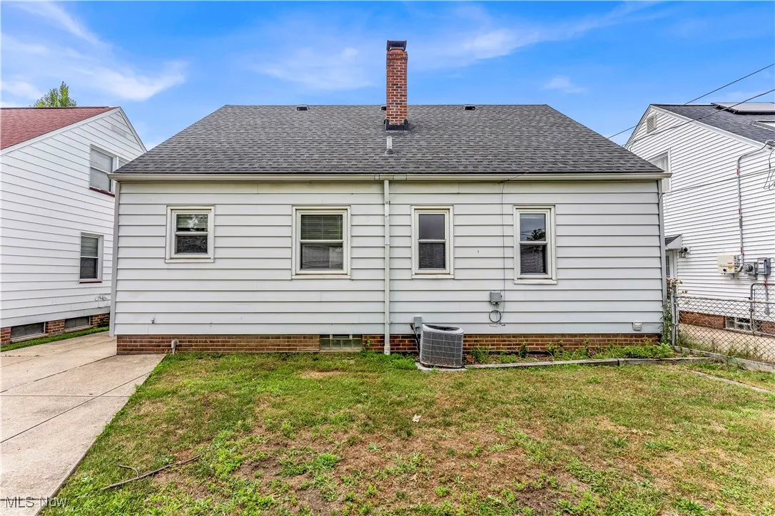 Back of house featuring a shingled roof and a chimney