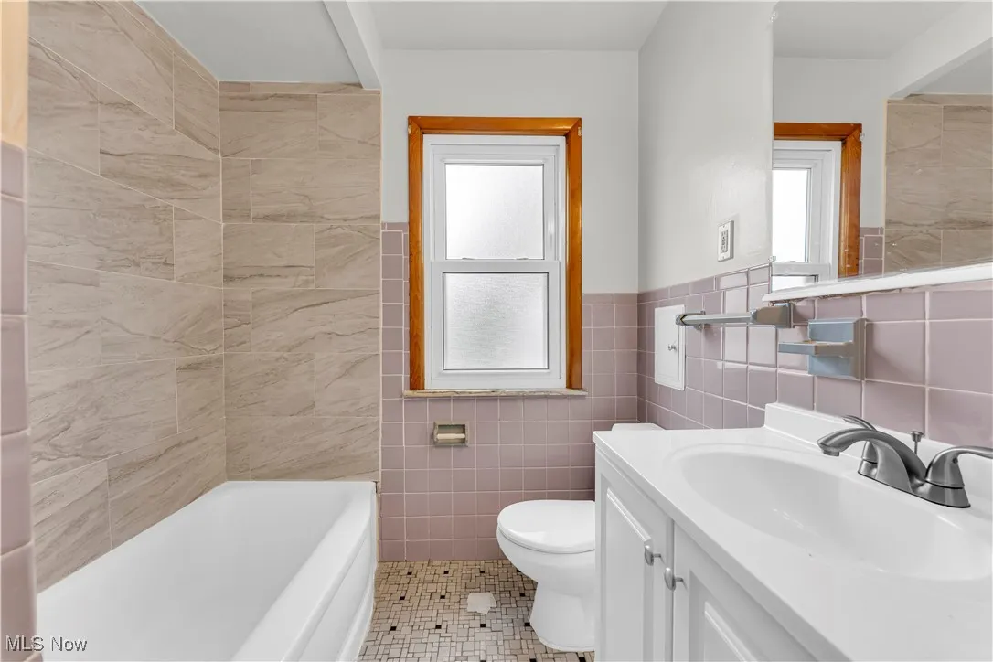 Bathroom with tile walls, vanity, tile patterned floors, and a wainscoted wall