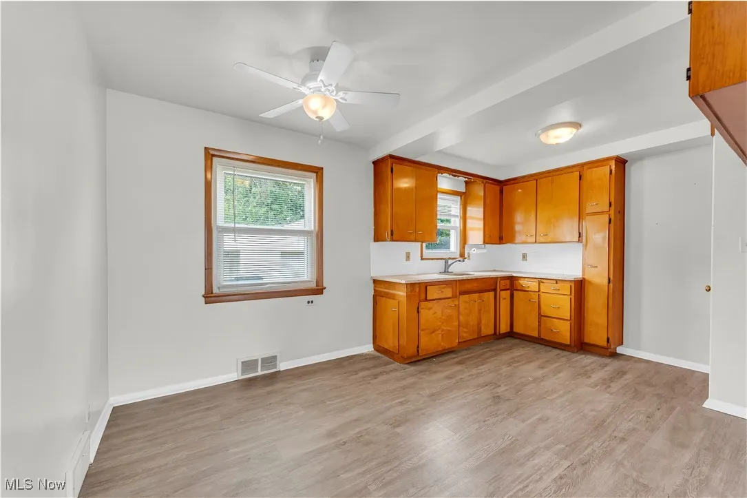 Kitchen with light countertops, light wood-style floors, a ceiling fan, and brown cabinets