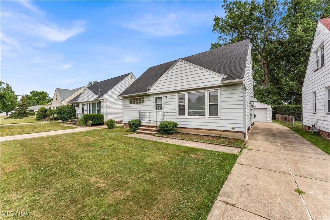 View of front of home featuring a shingled roof, an outbuilding, a front yard, and a​​‌​​​​‌​​‌‌​‌‌​​​‌‌​‌​‌​‌​​​‌​​ garage