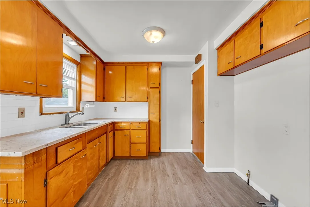 Kitchen with light wood-style flooring, light countertops, decorative backsplash, and brown cabinets